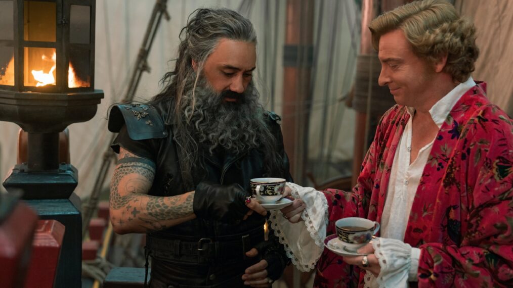 Bearded pirate Blackbeard and aristocrat Stede share tea on a pirate ship
