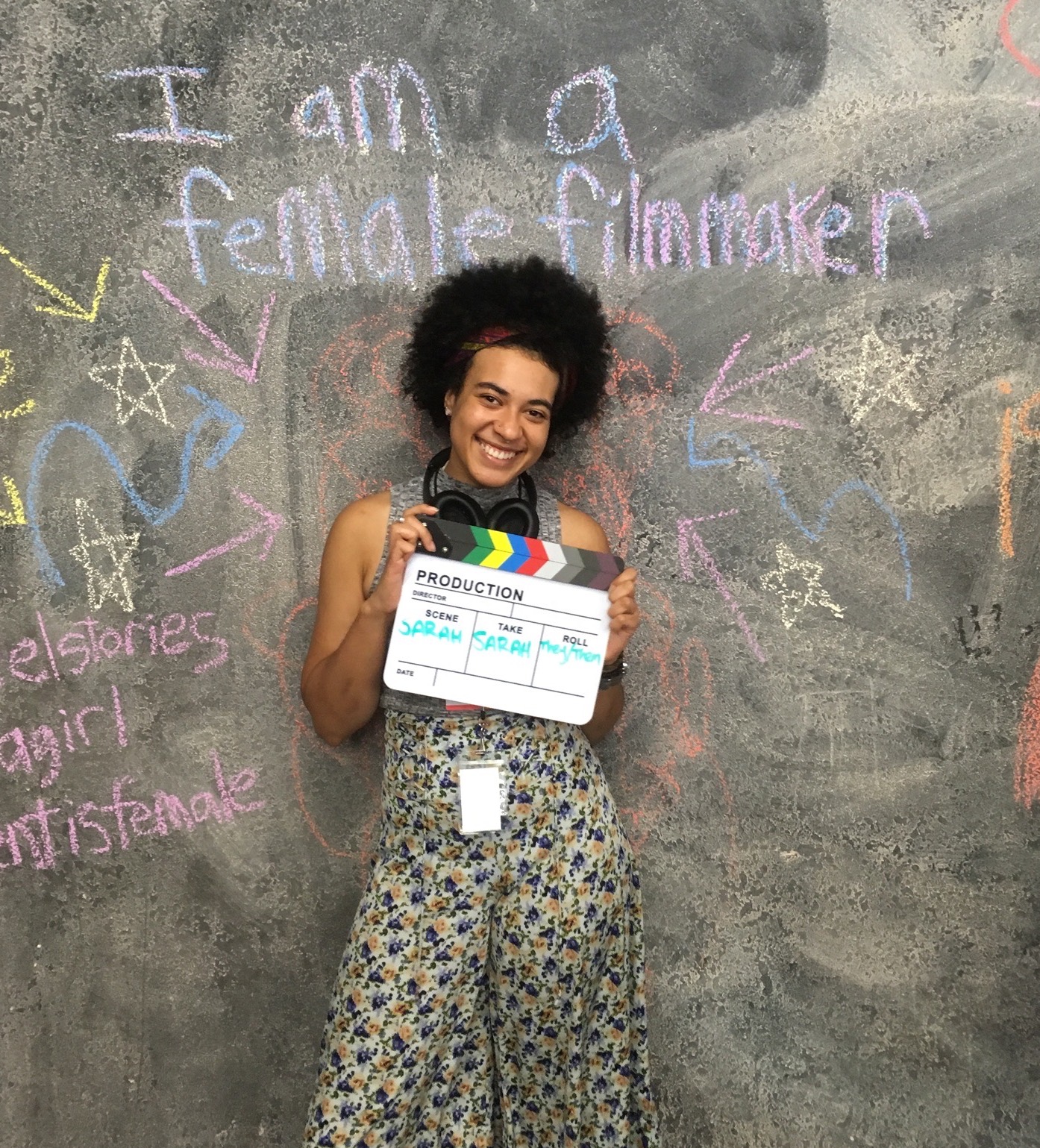 Liz Tril, a young woman with brown hair up in a bun, looks through the lens of a digital camera.